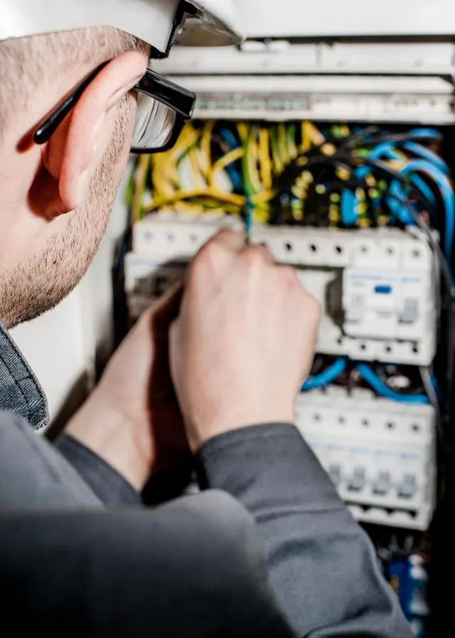 Électricien casqué intervenant sur un tableau électrique