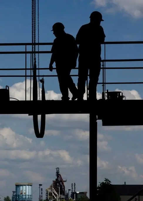 Silhouettes de deux ouvriers sur une passerelle d'échafaudage